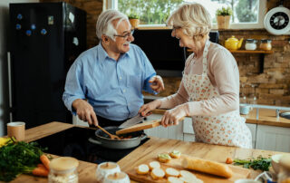 Happy senior couple smiling and cooking in kitchen