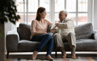 A senior man and his daughter talk on a sofa