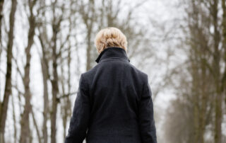 A senior walks alone in a park on a winter's day