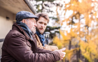 A senior man and his son stop to talk while on a walk outdoors