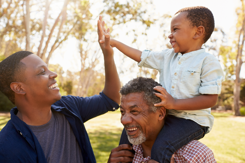 A senior man and his son and grandson go for a walk outdoors at the memory care in Macomb, MI