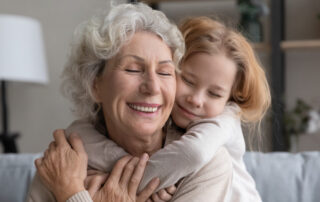 A senior woman getting hugged by her granddaughter