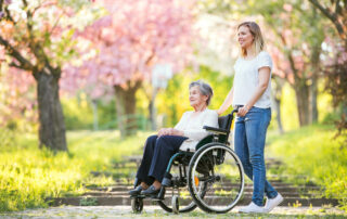 A senior woman using a wheelchair on a walk with her daughter outdoors at the senior housing near me