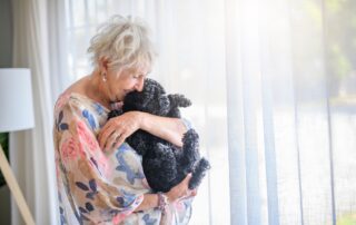 A senior woman hugs her black dog at the best assisted living in Michigan